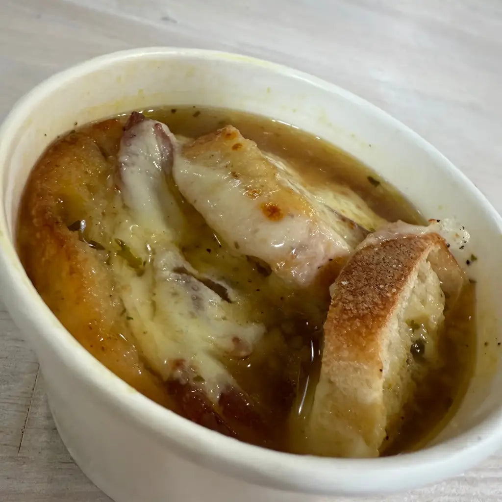 French onion soup with bread in a white bowl on a wooden table
