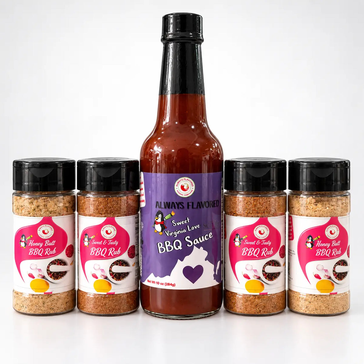 A tall glass bottle of sweet virginia love bbq sauce with a purple label and black cap surrounded by four honey butt bbq rub jars