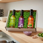 Kitchen scene with a box of hot sauce bottles on a counter, person cooking in the background