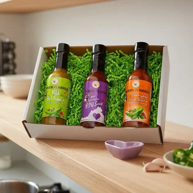 Kitchen scene with a box of hot sauce bottles on a counter, person cooking in the background