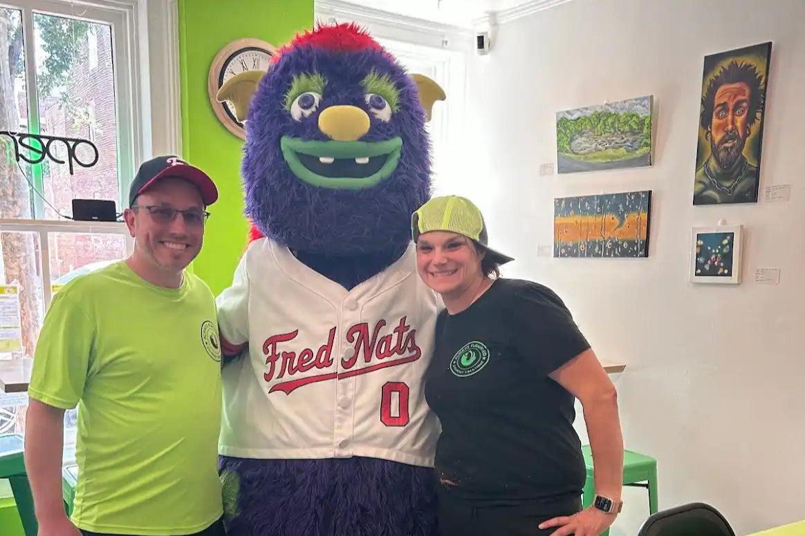 A furry blue and purple mascot wearing a Fred Nats baseball jersey.