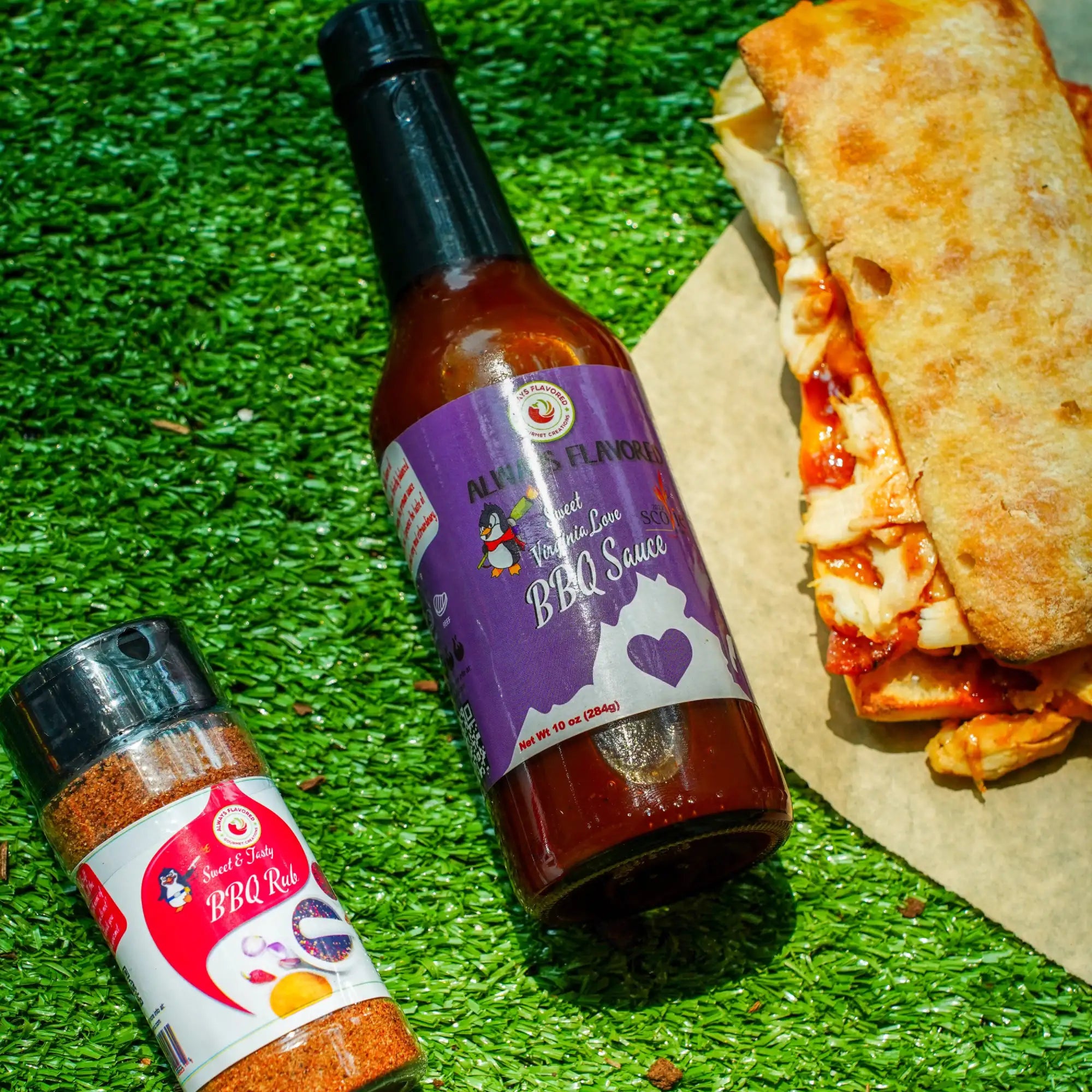 Two bottles of barbecue sauce on a green surface with a sandwich in the background