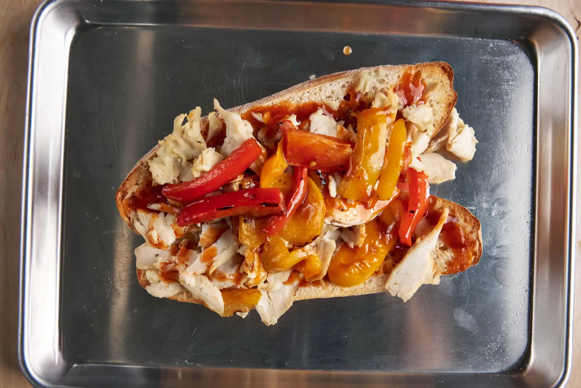 Sandwich filled with roasted bell peppers and shredded chicken on a split roll.