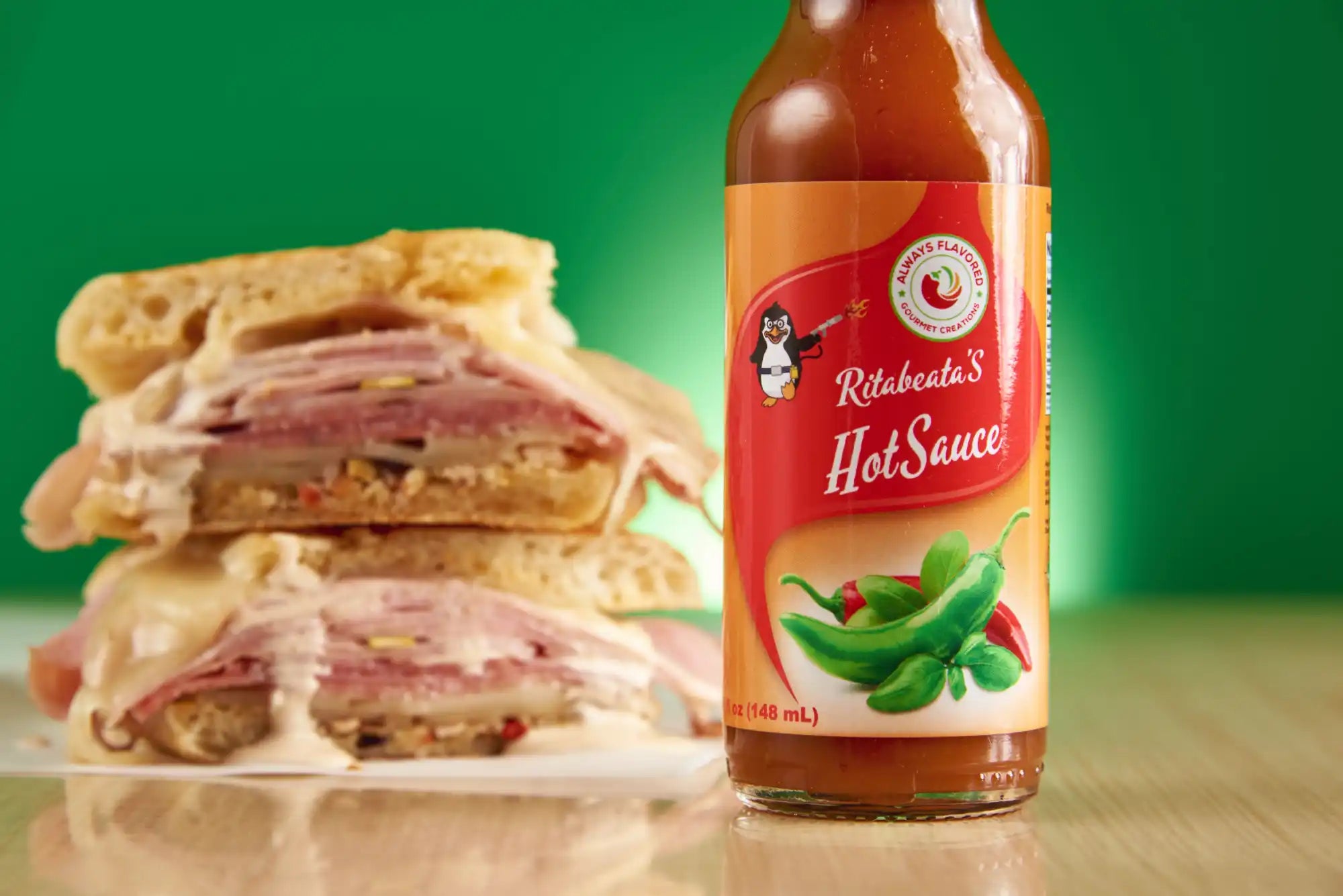 Stacked ham sandwich with a bottle of Richelieu’s hot sauce beside it.