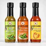 Three glass bottles of always flavored hot sauce with black caps and colorful labels in the rita heat flight collection