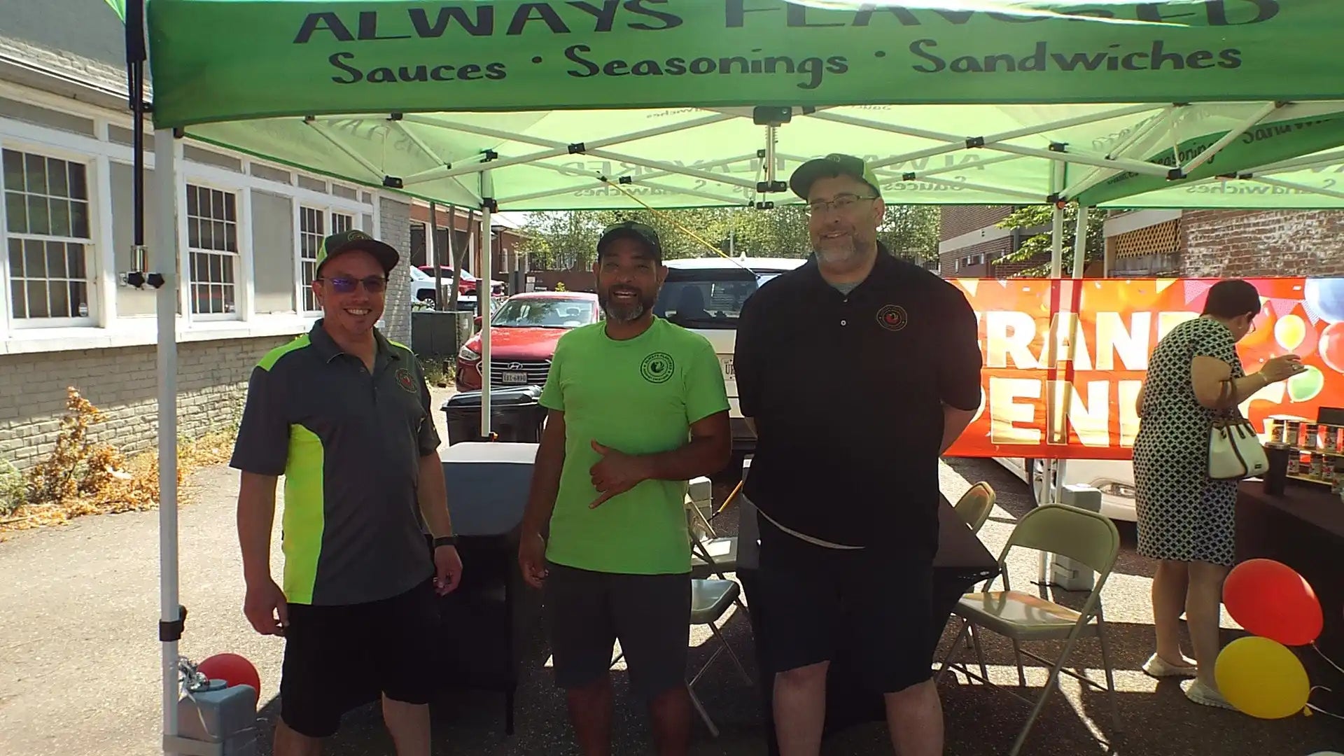 Three people standing together under a green canopy tent.