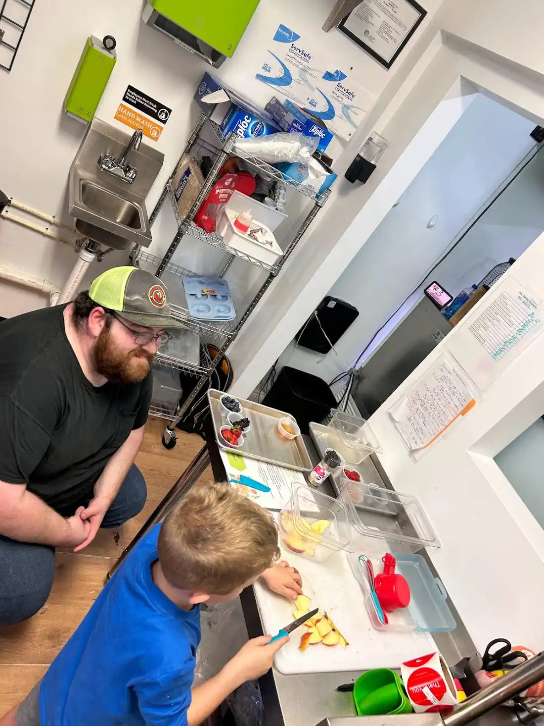 Two people working together at a desk with art supplies and materials.