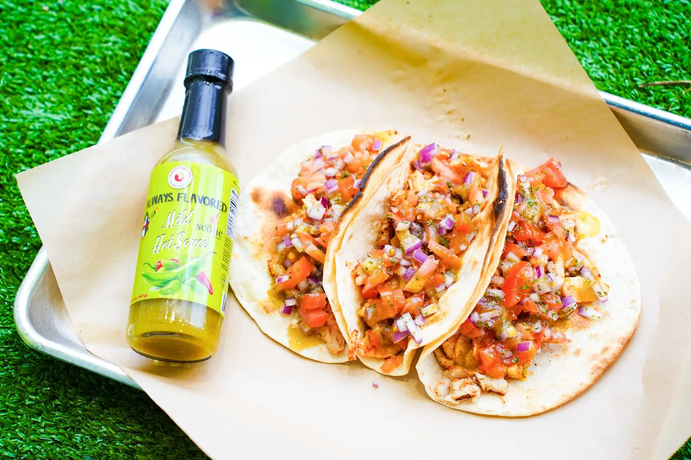 A vibrant yellow bottle of always flavored mild sauce with a black cap and green label featuring chili peppers.