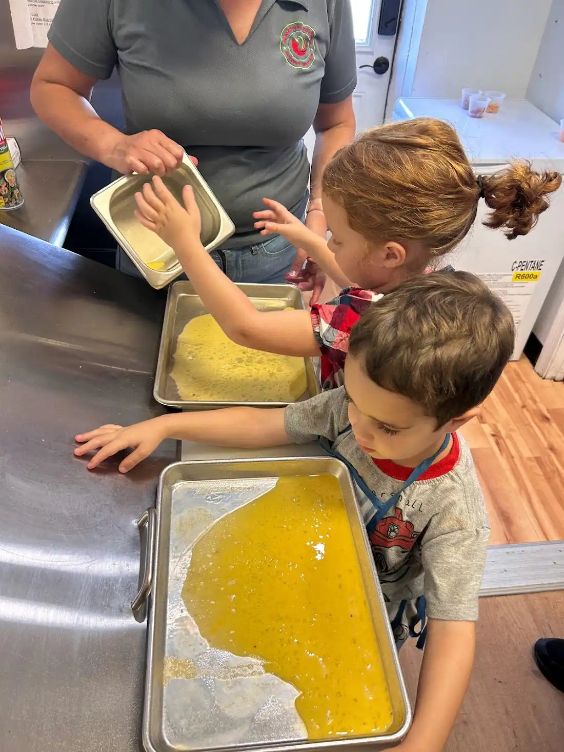 Yellow liquid or batter spread across metal baking trays.